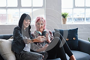 Phone, social media and students with women friends sitting on a sofa in the campus breakroom at college. Education photo