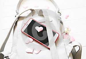 Phone, stylish bag and perfumes on white background. Beautiful flat lay with hearts. The best present for the girl. Woman`s or