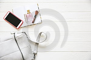 Phone, stylish bag and perfumes on white background. Beautiful flat lay. Things for business woman. Note book schedule. Makeup kit