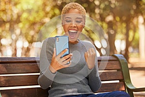 Phone, success and woman excited about trading on the internet while on a bench in the park. Young, happy and girl with