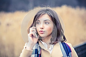 Phone talk. Closeup portrait. Serious woman talking on mobile phone outside outdoors on autumn park background, professional