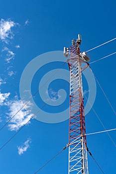 Phone tower antenna with blue sky and cloud background