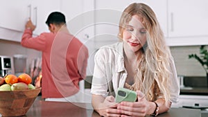 Phone, typing and woman on table in kitchen at home for social media, network or reading email with man. Smartphone