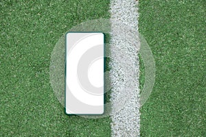 A phone with a white screen lies on a football field near a white stripe, a mobile phone