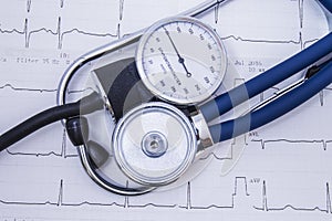 Phonendoscope or stethoscope and sphygmomanometer dial with normal physiological indicators of arterial lies on the paper electroc