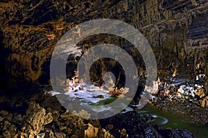 Phong Nha Ke national park / Vietnam, 16/11/2017: Group of cavers passing an underground river and huge rocks inside the giant photo