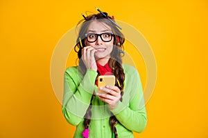 Phoro of frightened girl messy hairdo bite nails hold smartphone wear shirt isolated yellow color background