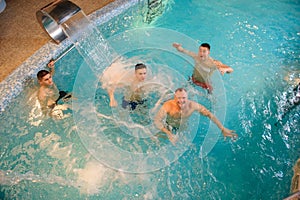 Photo of 4 men relaxing on the top of a swimming pool in a spa centre