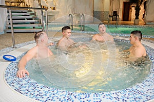 Photo of 4 men relaxing on the top of a swimming pool in a spa centre