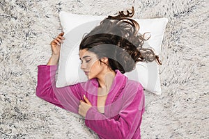 Photo from above of attractive woman wearing girlish housecoat lying and sleeping on white fur in apartment photo