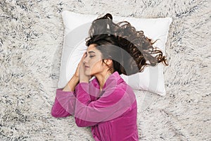 Photo from above of brunette woman wearing girlish housecoat lying and sleeping on white fur in apartment photo