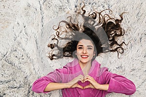 Photo from above of european woman wearing girlish housecoat lying on white fur in apartment photo