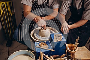 Photo from above. The hands of a man and a woman make a clay vase on a machine using an apparatus. Dating concept