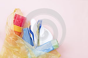 A photo from above of Plastic disposable tableware, spoons, forks, cups and bags. Zero waste, environmental pollution. Save the