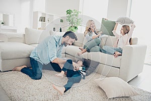 Photo of adopted family four members spend free time pillows fight giggle sit couch living room