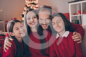 Photo of adorable attractive son daughter dad mom wear red pullovers smiling celebrating christmas hugging indoors house