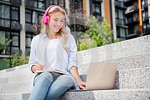 Photo of adorable charming pretty woman working remotely listening video conference and writing notes in copybook