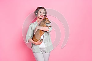 Photo of adorable charming young lady wear beige outfit smiling hugging small puppy empty space isolated pink color