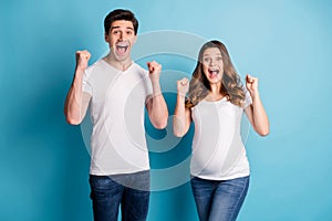 Photo of adorable cheerful charming attractive lucky couple expecting child rising fists isolated blue color background