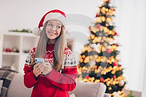 Photo of adorable cheerful girl toothy smile hold use telephone newyear magic atmosphere house indoors