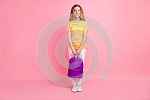 Photo of adorable cheerful positive girl toothy smile wear backpack striped yellow t-shirt isolated pink color