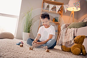 Photo of adorable cute boy sitting floor in play room home have free time make words with abc blocks