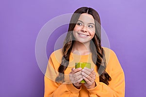 Photo of adorable dreamy lady wear orange sweatshirt enjoying beverage looking empty space isolated violet color