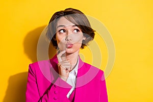 Photo of adorable dreamy young woman dressed pink suit finger pouted lips looking empty space isolated yellow color