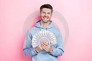 Photo of adorable good mood guy dressed blue sweatshirt smiling rising money fan isolated pink color background