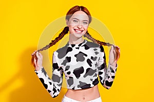 Photo of adorable good mood lady dressed cowskin top smiling holding braids isolated yellow color background photo