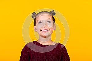 Photo of adorable intelligent minded girl toothy smile look up empty space isolated on yellow color background