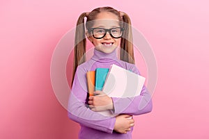 Photo of adorable little sweet clever schoolgirl go on first day of school isolated on pink color background