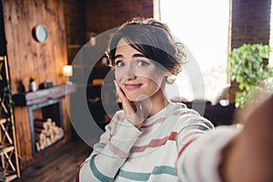 Photo of adorable peaceful girl hand touch cheek take selfie sunlight window pastime modern apartment inside