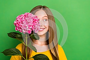 Photo of adorable positive girl toothy smile look empty space pink flower cover one eye  on green color