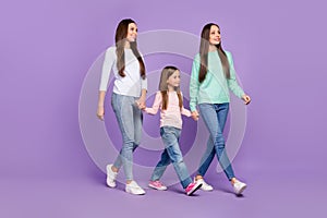 Photo of adorable pretty daughters mom dressed sweaters walking holding hands looking empty space isolated purple color