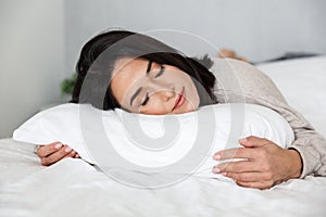 Photo of adult woman 30s sleeping, while lying in bed with white linen at home