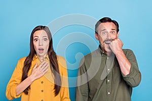 Photo of afraid shocked scared mature man and woman horrified bad mood isolated on blue color background
