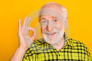 Photo of aged man happy positive smile show okay sign sign deal done alright advert isolated over yellow color