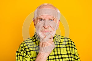 Photo of aged man pensioner angry serious hand touch chin think minded isolated over yellow color background