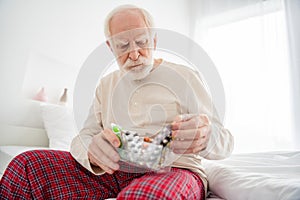 Photo of aged man pensioner unhappy unwell unhealthy ill look meds pills painkiller sit bed home indoors