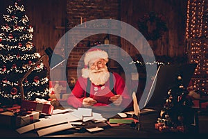 Photo of aged santa claus happy positive smile read letters wish workshop new year lights decor noel indoors