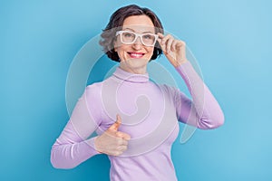Photo of aged woman happy positive smile hand touch eyeglasses show thumb-up fine perfect ad isolated over blue color