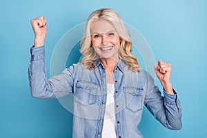 Photo of aged woman happy positive smile rejoice victory ecstatic lucky fists hands isolated over blue color background