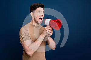 Photo of aggressive mad man wear trendy beige clothes hold bullhorn shout scream look empty space isolated on dark blue