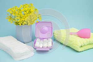 A photo of alarm clock, menstrual pads, terry towel, tampons and menstrual cup for blood period. Menstruation period pain