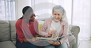 Photo album, retirement home and a senior laughing with her black woman caregiver on a sofa in the living room. Smile