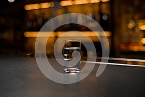 photo of a alcoholic shot on grey bar counter on blurred background