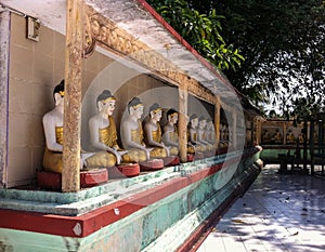 Photo of aligned Buddha statues in a temple in Thailand. Aligned statues of Buddha. Buddhist temple.