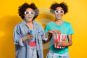 Photo of amazed afro american people couple wear 3d glasses fly pop corn drink isolated on yellow color background