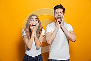 Photo of amazed couple man and woman in basic clothing screaming